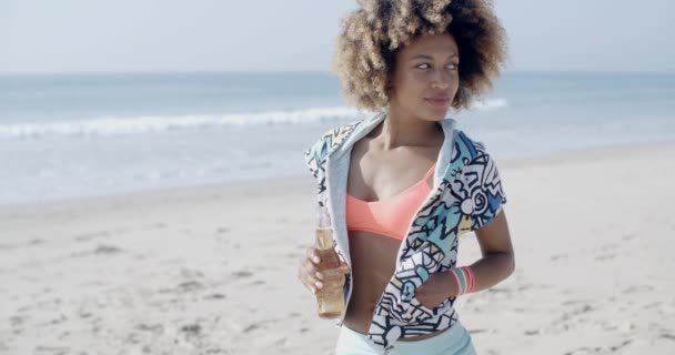 Woman holding bottle against seashore - Filmati, video
