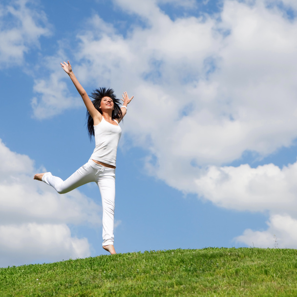 Mujer bastante joven saltando sobre hierba verde
 - Foto, Imagen