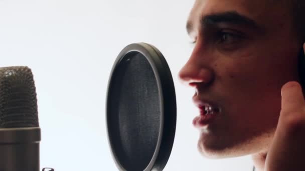 Young, handsome singer singing into a microphone headphones holding hands. - Materiał filmowy, wideo