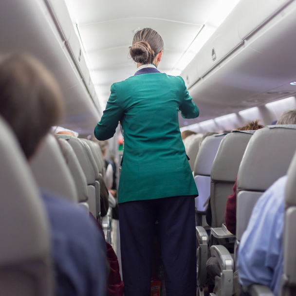 Stewardessand passagiers op commerciële vliegtuig. - Foto, afbeelding
