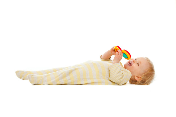 Cute kid laying on floor with rattle isolated on white - Fotó, kép