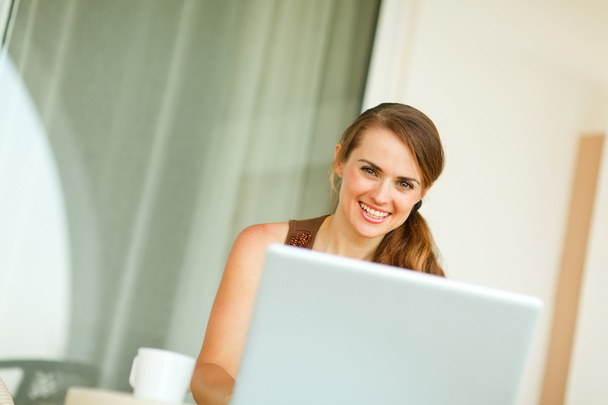 Portrait of smiling woman working on laptop - Foto, afbeelding