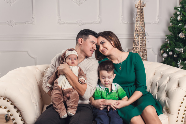 A young happy family of four in new year interior - Photo, Image