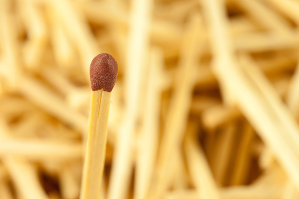 Single matchstick on blurred background of wooden sticks - Photo, Image