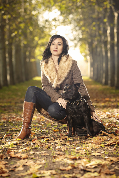 Autumn beauty and her dog in park - Foto, afbeelding