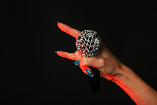 Femme main avec microphone et cornes du diable sur noir
 - Photo, image