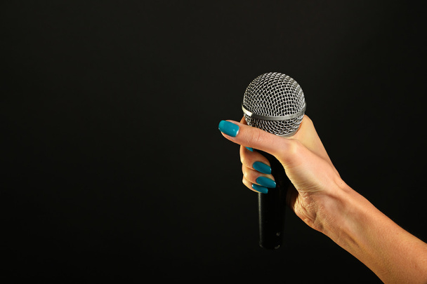 Mano de mujer con micrófono aislado en negro
 - Foto, Imagen