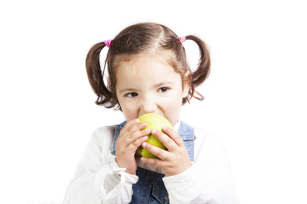 Portrait of happy girl biting a green apple - Foto, afbeelding