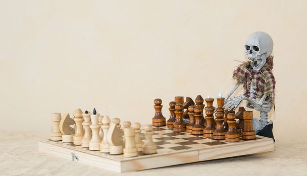 Divertido esqueleto sentado detrás de la mesa y jugando al ajedrez
 - Foto, imagen