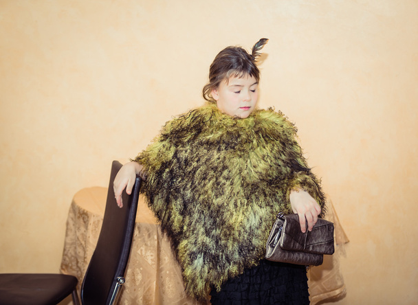 Стильная модная маленькая девочка с закрытыми глазами в лама зеленый мех пончо
 - Фото, изображение