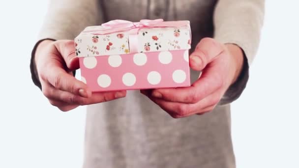 Handsome guy gives a gift in the box for his birthday. Cute guy standing on a white background and smiling. - Video
