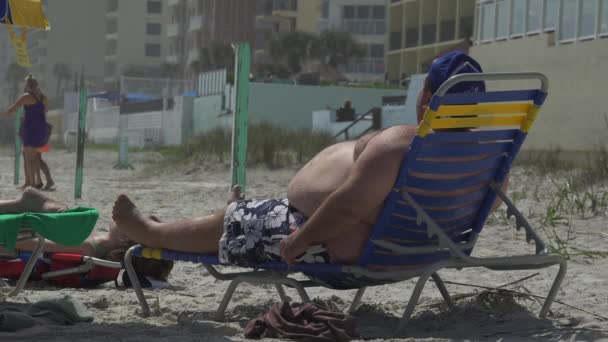 Παχύσαρκος άνθρωπος χαλαρώνετε σε μια παραλία - Πλάνα, βίντεο