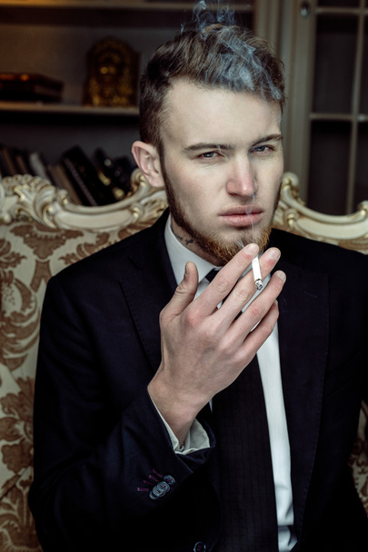Man sitting in vintage chair with a cigarette - Photo, Image