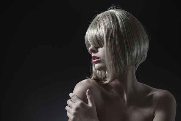 Portrait of a blond woman over a dark background - Photo, Image