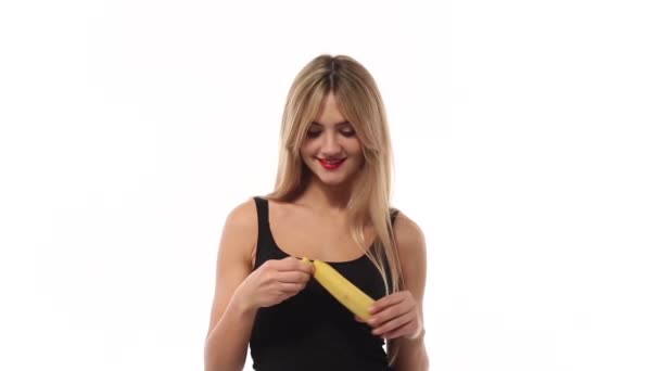 Woman eating sweet banana at white background - Footage, Video