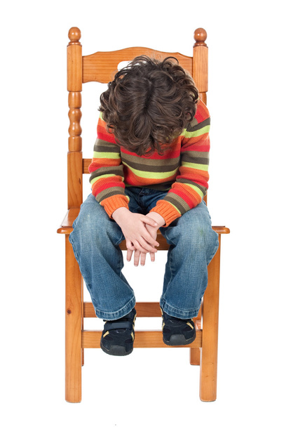 θλιβερό παιδί κάθεται σε μια καρέκλα που απομονώνονται - Φωτογραφία, εικόνα