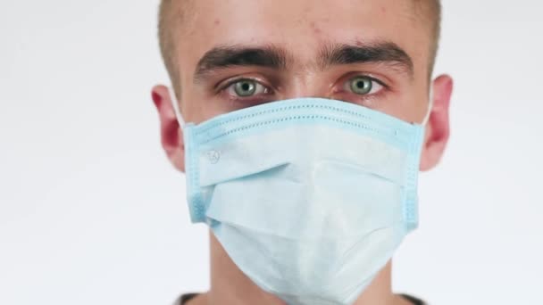 Handsome young man in a medical mask on his face looking at the camera. At the end of the lights. - Footage, Video