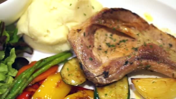 grilled pork chop and salmon steak with mash potato and gravy. Side dish of colourful salad and vegetable - Footage, Video