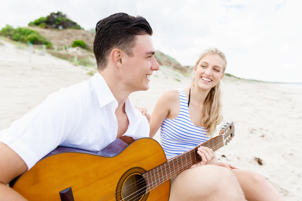 Young couple playing guitar on beach in love - Fotoğraf, Görsel