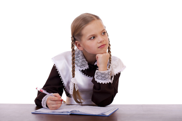 Young beautiful schoolgirl sitting at a desk - Zdjęcie, obraz