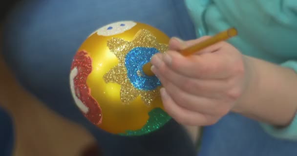 Mujer de manos femeninas en azul sostiene juguete dorado bola de árbol de año nuevo se levanta y se aleja La bola está pintada decorada con diferentes brillos de color
 - Metraje, vídeo