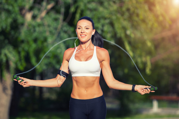 fitness and lifestyle concept - woman doing sports outdoors. girl with skipping rope - 写真・画像