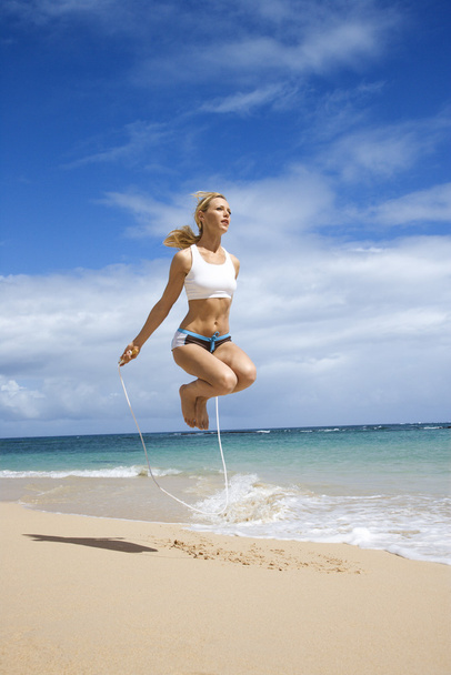 Woman jumping rope on beach. - Fotó, kép