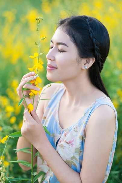 Aziatische vrouw ruikende bloemen. Ontspannen door therapie van het Aroma. - Foto, afbeelding