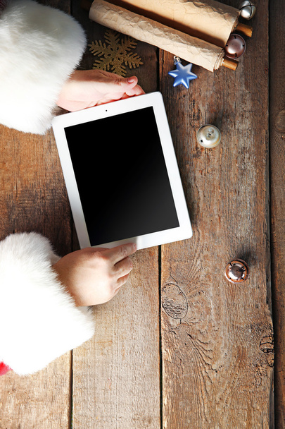 Christmas concept. Santa with tablet in hands over wooden table, close up - Фото, зображення