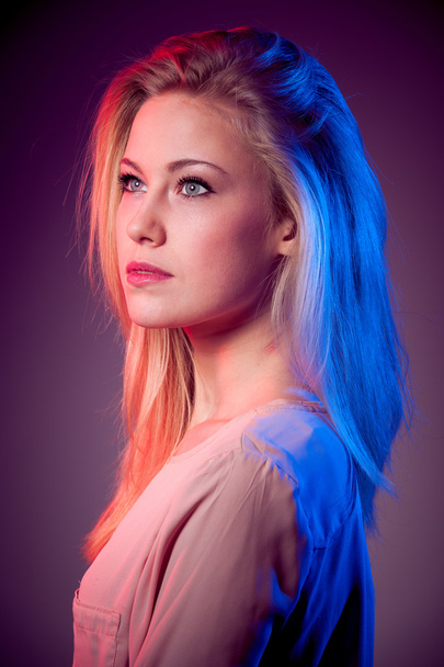 Beauty portrait of young blonde woman with red and blue light on hair - Photo, image