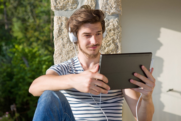 genç adam bir kulaklık, açık ile müzik dinleme tablet pc ile rahatlatıcı - Fotoğraf, Görsel
