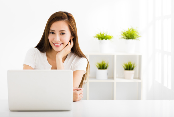 Счастливая молодая женщина с ноутбуком в гостиной
 - Фото, изображение