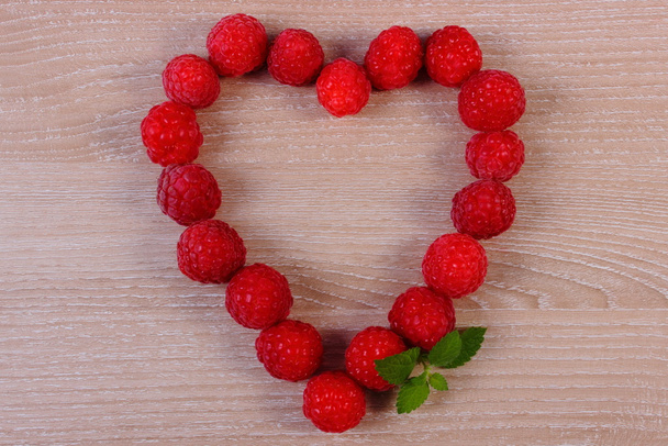 Heart of fresh raspberries on wooden table, symbol of love - Фото, изображение