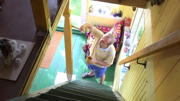 Dospělý pracovník maluje nový dřevěný sloup s kartáčem na schodech. 4k - Záběry, video