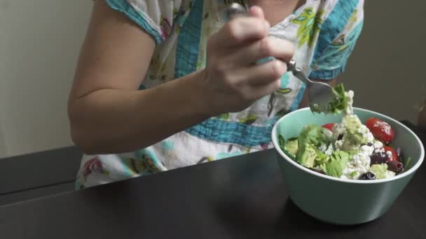 Μια γυναίκα απολαμβάνει μια σαλάτα ενώ κάθεστε σε κάποιο το dinning πίνακα δωματίων σας. - Πλάνα, βίντεο
