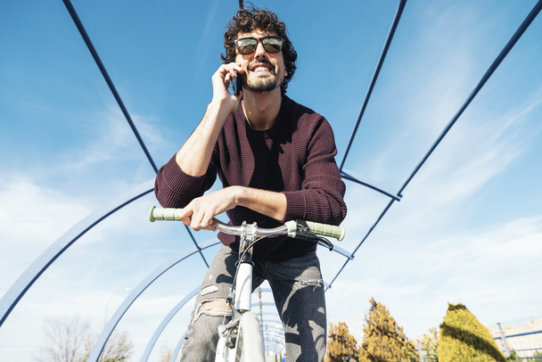 Handsome young man with mobile phone and fixed gear bicycle. - Zdjęcie, obraz