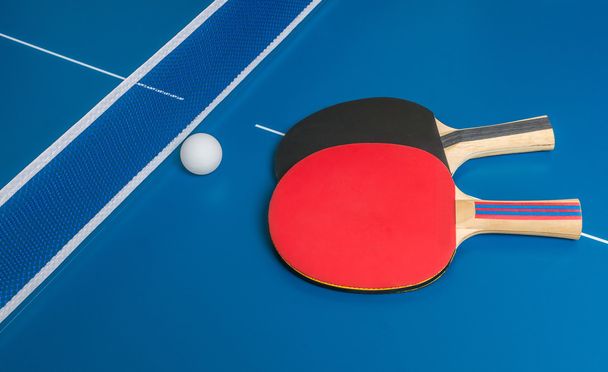 Reto de ping pong. Raquetas de tenis de mesa sobre mesa azul
. - Foto, Imagen