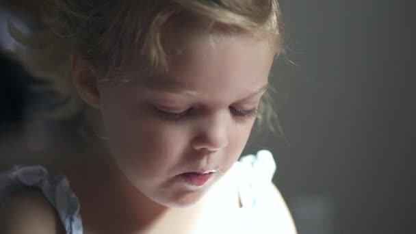 Ένα παιδί απολαμβάνει ένα σνακ ενώ κάθεστε σε κάποιο το dinning πίνακα δωματίων σας - Πλάνα, βίντεο