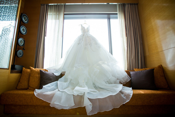 Weißes Hochzeitskleid hängt an den Schultern - Foto, Bild