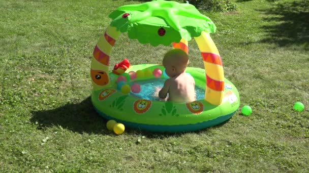 Bebé adorable bebé divertirse en la piscina de agua del centro comercial con bolas de colores en el prado del jardín. 4K
 - Imágenes, Vídeo