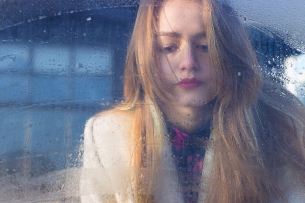 sad beautiful seksalnaya Pretty sad lonely girl behind wet glass with big sad eyes in a coat - Foto, Bild