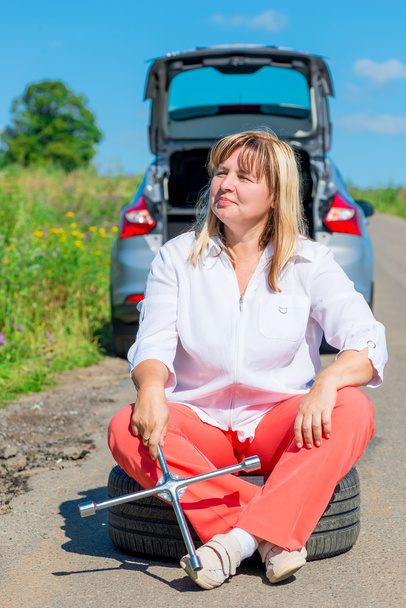unavená žena po výměně prasknutí kola spočívá - Fotografie, Obrázek