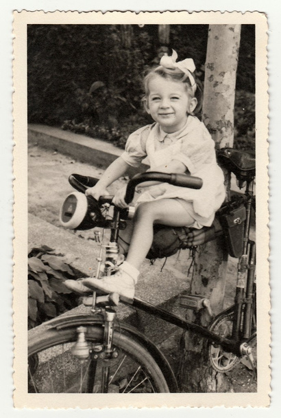 A small girl on bike. Vintage photo was taken in Hodonin (the Czech Republic). Early forties. - Foto, afbeelding