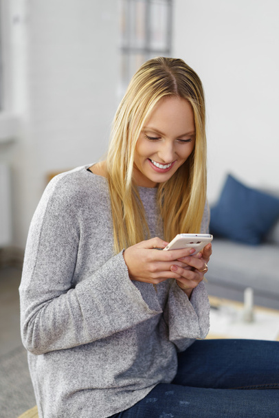 Young blond woman reading a text message - Zdjęcie, obraz