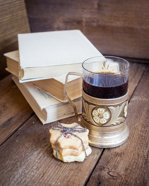 Book, cookies and tea in coaster on wooden background - Photo, Image