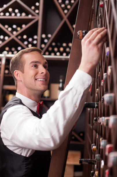 Cheerful male waiter is looking for perfect beverage - Foto, imagen