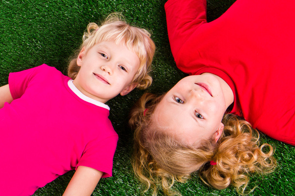 Group of happy children lying on a green grass - Photo, image