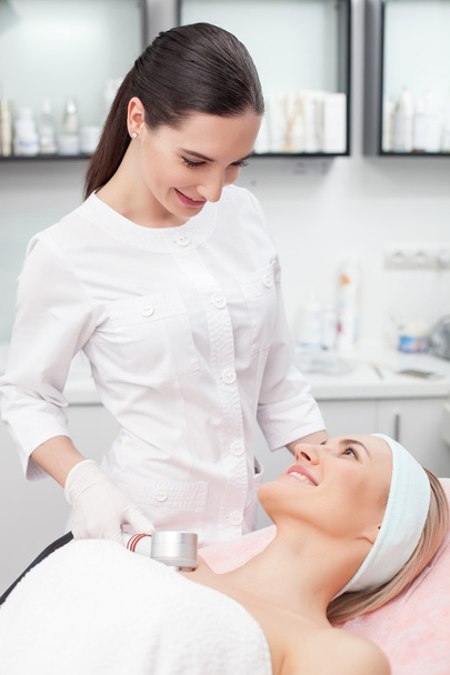 Attractive young beautician is treating her patient - Foto, afbeelding