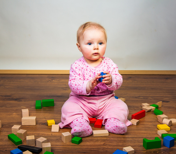 Дитяча дівчина грає в кімнаті на дерев'яній підлозі
 - Фото, зображення