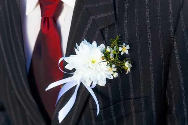 Nahaufnahme schwarzer Sakko-Bräutigam am Hochzeitstag mit roter Krawatte und Knopfloch am Revers. - Foto, Bild